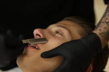 Berber dükkanında müşteriyle çalışan profesyonel berber, yakın plan.