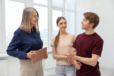 Evde çiftlerle çalışan tabletli bir emlakçı.