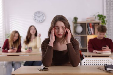 Siber zorbalık. Sınıfta masasında akıllı telefonu olan üzgün bir genç kız.