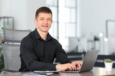 Ofisteki masada dizüstü bilgisayarda çalışan bir adam. Metin için boşluk