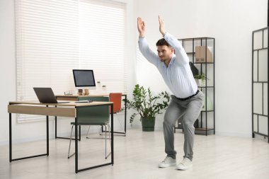 Ofiste masa başında egzersiz yapan yakışıklı bir adam.