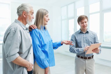 Tabletle gülümseyen emlakçı evde çiftlerle çalışıyor.