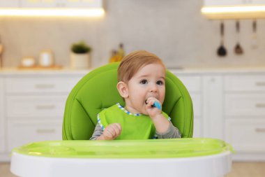 Küçük şirin bir bebek. Kapalı bir sandalyede kaşık var.