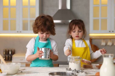 Yemek tarifi. Mutfaktaki masada un elemekte olan sevimli çocuklar.