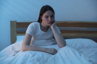 Yatakta uykusuzluk çeken sinirli genç bir kadın.