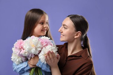 Anne ve kızı mor arka planda bir buket güzel şakayıkla