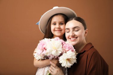Anne ve kızı kahverengi arka planda bir buket güzel şakayıkla mesajlaşmak için yer açıyorlar.