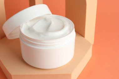 Turuncu arka plandaki kavanozda nemlendirici vücut kremi sunumu, yakın plan. Metin için boşluk