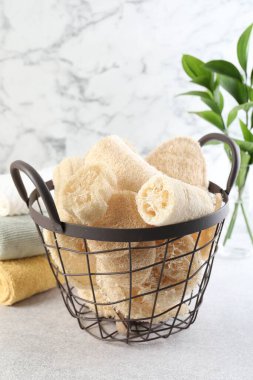 Sepette farklı lif süngerleri ve açık gri masada havlular.