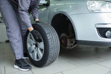 Tamirci araba servisinde lastik değiştiriyor, yakın plan.