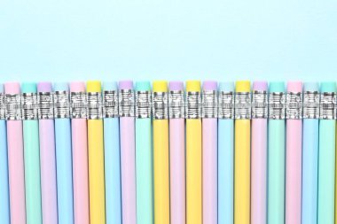 Açık mavi arkaplanda silgileri olan çizgili kalemler, düz yatış