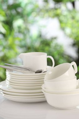 Bulanık yeşil arka planda beyaz masada farklı temiz tabaklar