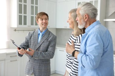 Mutfakta çiftlerle çalışan gülümseyen emlakçı.