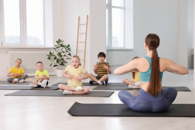 Sınıfta koçla yoga yapan bir grup çocuk.