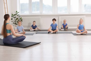 Sınıfta koçla yoga yapan bir grup çocuk.