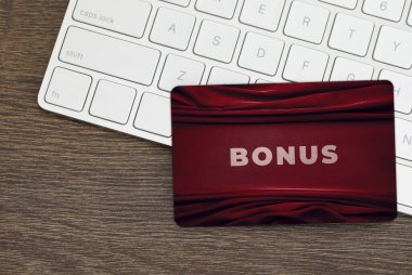 Şık tasarımı olan bonus kart ve tahta masa üzerinde bilgisayar klavyesi, üst görünüm