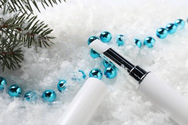 Nemlendirici dudak kremi, Noel dekorasyonu ve yapay kar üzerindeki köknar ağacı dalları, yakın plan. Kış bakımı