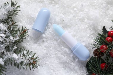Nemlendirici dudak kremi, Noel dekorasyonu ve yapay kar üzerinde köknar ağacı dalları. Kış bakımı