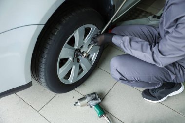 Tamirci araba servisinde lastik değiştiriyor, yakın plan.