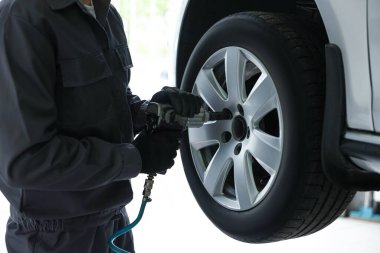 Tamirci araba servisinde lastik değiştiriyor, yakın plan.