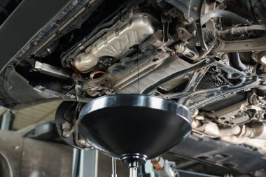 Araba motorundan konteynıra kirli motor yağı damlıyor atölyede, yakın plan