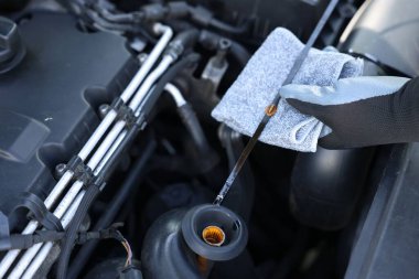 İşçi arabada motor yağı seviyesini dipstick ile kontrol ediyor.