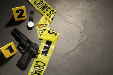 Adli tıp uzmanlığı. Gri arka planda delil, işaretler ve polis bandı olan bir suç mahalli. Metin için boşluk