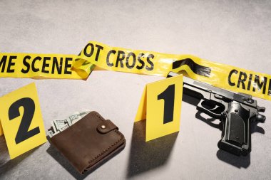 Adli tıp uzmanlığı. Açık gri arka planda delil, işaret ve polis bandı olan suç mahalli, yakın plan