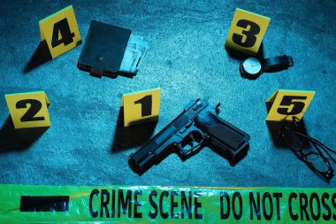 Adli tıp uzmanlığı. Deliller, işaretler ve mavi arka planda polis bandı olan bir suç mahalli. Renkli tonlama efekti