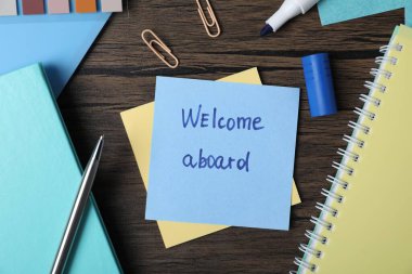 Sözcüklü kağıt not Gemiye hoş geldiniz ve ahşap masa üzerinde kırtasiye, düz yatıyordu