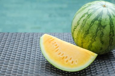 Açık havuz kenarında hasır masada sarı karpuzlar var. Yakın plan. Metin için boşluk