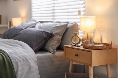 Yumuşak çarşaflı, komodinli ve lambalı rahat bir yatak. Ev tekstili