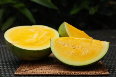 Hasır masada olgun sarı karpuz parçaları, yakın plan.