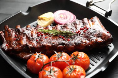 Biberiyeli domuz pirzolası, domates ve soğan. Gri ahşap masada, yakın plan.