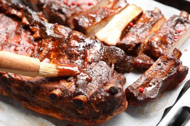 Fırçayla sosu pişirme tepsisindeki kaburgaların üzerine serpiştiriyorum.