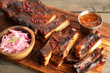 Lezzetli domuz pirzolası, sos ve soğan ahşap masada, yakın plan.