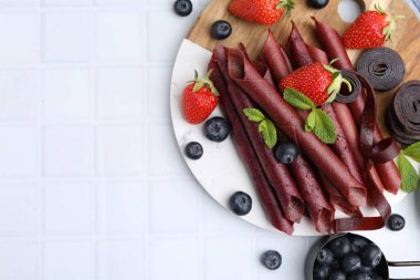 Lezzetli meyve dürümleri, çilekler, yaban mersinleri ve nane şekeri beyaz fayanslı masa, düz yatak. Metin için boşluk