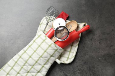 Mutfak aletleri, fırın eldivenleri, gri masa, üst manzara.