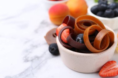 Lezzetli meyve derisi kase içinde yuvarlanıyor ve beyaz mermer masada böğürtlenler, yakın plan. Metin için boşluk