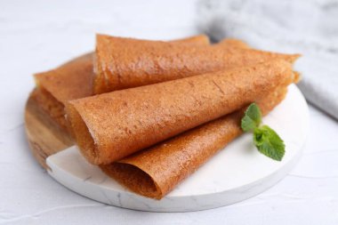 Lezzetli meyve dürümleri ve nane şekeri beyaz masada, yakın plan.