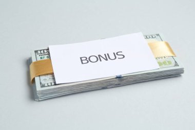 Açık gri arka planda kelime bonusu ile dolar banknotları ve kart, yakın plan