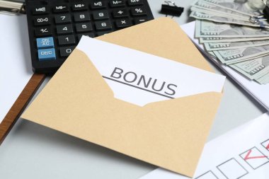 Açık gri arkaplan üzerinde bonus, para, hesap makinesi ve kağıt işleriyle zarf, yakın plan