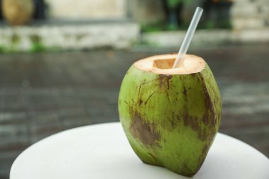 Yeşil hindistan cevizi, ferahlatıcı bir içecek ve açık havada beyaz masada saman, yakın plan. Metin için boşluk