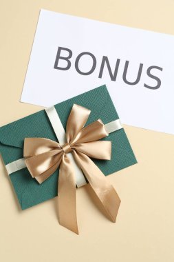 Zarfta altın fiyonk ve kart var. Bej arka planda bonus var.