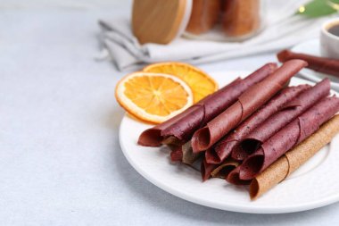 Lezzetli meyve dürümleri ve portakal dilimleri beyaz masada, yakın plan. Metin için boşluk