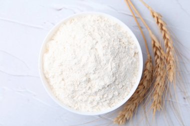 Buğday unu kasede, çiviler beyaz masada, düz yerde.