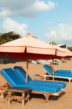 Güneş pansiyonları, plaj şemsiyesi ve tatil yerindeki ahşap masa.