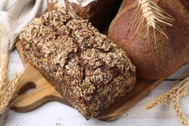 Taze ekmek somunları ve çiviler beyaz ahşap masada, yakın plan.