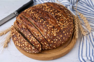 Taze pişmiş ekmek, yulaf gevreği ve hafif desenli masada çiviler, yakın plan.