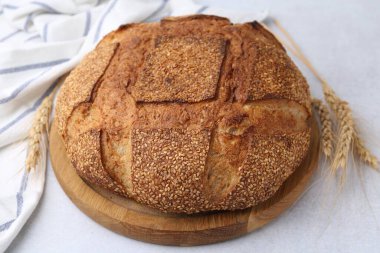 Taze pişmiş ekmek, susam tohumları ve açık gri masada çiviler, yakın plan.